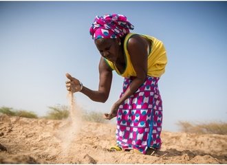 Woman in Senegal shows her dry and salinated paddy (ActionAid)