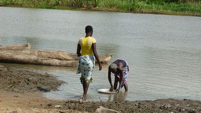 women wash dishes in the river near Cotonou, Benin